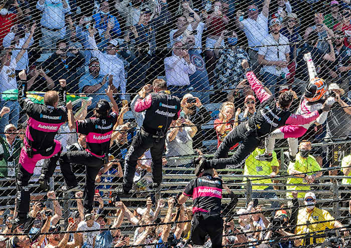 Helio Castroneves celebrates his Indianapolis 500 victory by climbing the fence at Indianapolis Motor Speedway.
